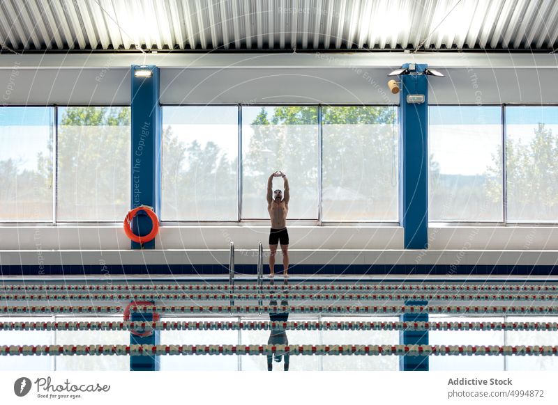 Schwimmer mit Schwimmbrille, die sich im Schwimmbecken spiegelt Athlet Schwimmsport Sport Pool stark nackter Torso maskulin Körper reflektieren Mann vorbereiten