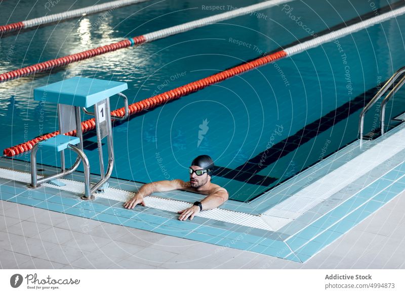 Schwimmer mit Schwimmbrille lehnt am Beckenrand sich auf die Hand lehnen Schutzbrille maskulin Mann Porträt Athlet Sport Macho müde Pool Accessoire Sportler