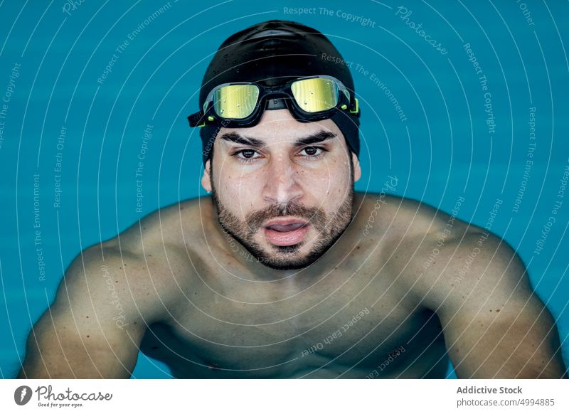 Schwimmer mit Schwimmbrille lehnt am Beckenrand sich auf die Hand lehnen Schutzbrille maskulin Mann Porträt Athlet Sport Macho müde Pool Accessoire Sportler