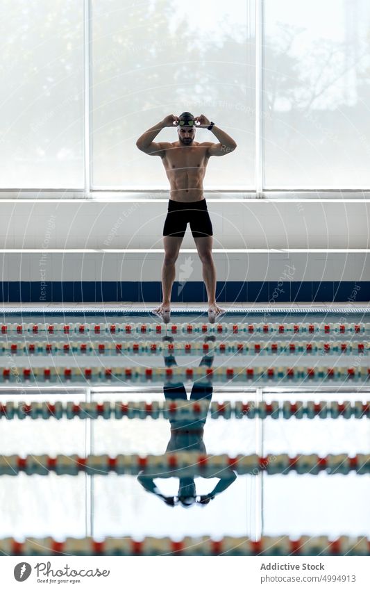 Schwimmer mit Schwimmbrille, die sich im Schwimmbecken spiegelt Athlet Schwimmsport Sport Pool stark nackter Torso maskulin Körper reflektieren Mann vorbereiten