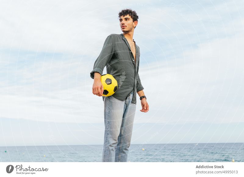 Hispanischer Mann hält Ball am Meer Strand MEER Kick Trick Sommer Wochenende Fußball männlich hispanisch ethnisch jung Aktivität Seeküste tagsüber lässig