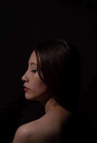 Frau im Profil bei schwacher Beleuchtung in einem dunklen Raum Low Key feminin Schatten 18-30 Jahre Mensch Junge Frau nachdenklich Erwachsene Schulter Gefühle