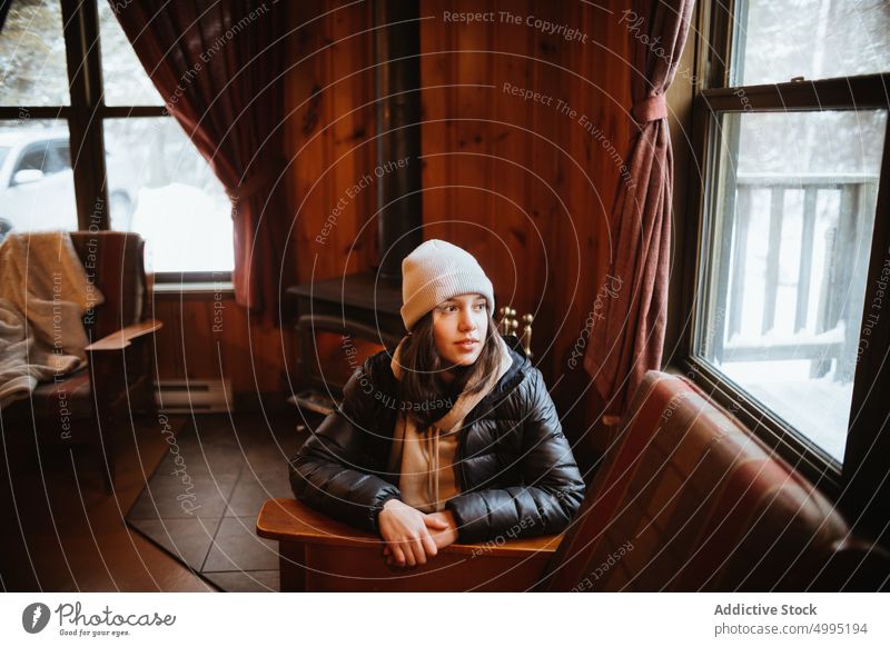 Weiblicher Reisender in Holzhütte Frau Hütte Beanie Wochenende Winter Ausflug Bank Fenster Hut besuchen Saison Tal der Geister Monts Valin Quebec Kanada