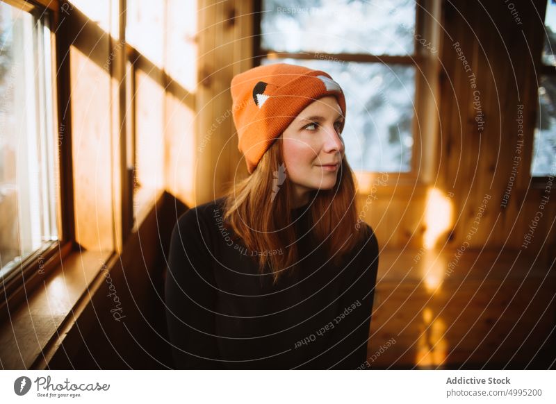 Weiblicher Reisender in Holzhütte Frau Hütte Beanie Wochenende Winter Ausflug Bank Fenster Hut besuchen Saison Tal der Geister Monts Valin Quebec Kanada