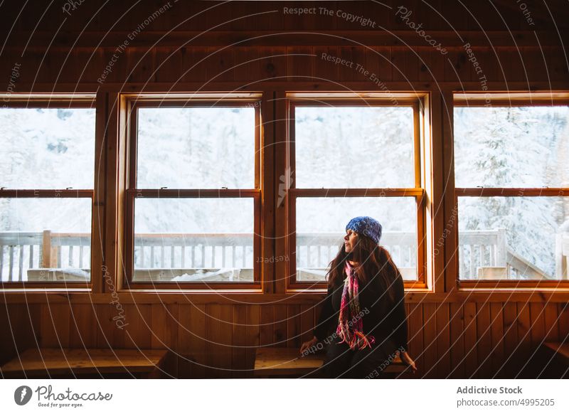 Weiblicher Reisender in Holzhütte Frau Hütte Wochenende Winter Ausflug Bank Fenster besuchen Saison Tal der Geister Monts Valin Quebec Kanada Nationalpark