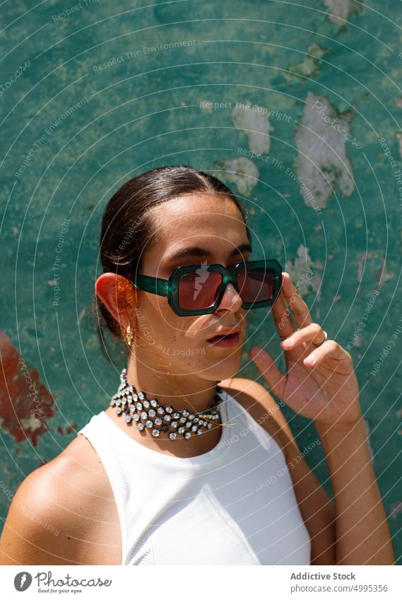 Selbstsichere ethnische stilvolle Dame, die im Sonnenlicht wegschaut Frau Sonnenbrille Mode Stil selbstbewusst Porträt Model ausrichten selbstsicher Vorschein