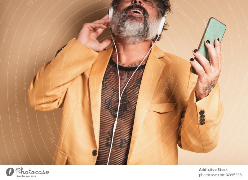 Älterer Mann, der mit Kopfhörern Musik hört zuhören singen exzentrisch Atelier genießen Gesang expressiv männlich Vollbart Audio Klang Stil Stimme Apparatur