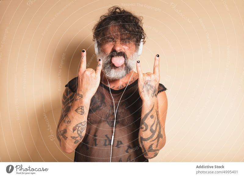 Bärtiger Mann zeigt Rock-Geste und hört Musik Rocker Felsen gestikulieren auflehnen zuhören ausspannen Rock and Roll Hupe männlich reif Mittelfinger grauer Bart