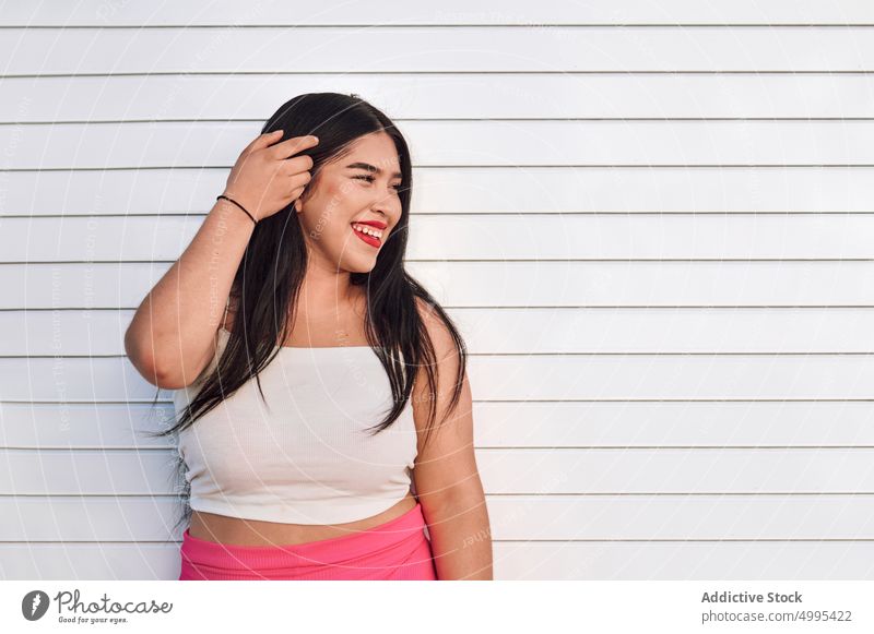 Stilvolle plus Größe Frau steht auf der Straße Lächeln weiß Wand urban Vorschein Übergröße Glück ethnisch jung heiter Übergewicht mollig froh tagsüber positiv