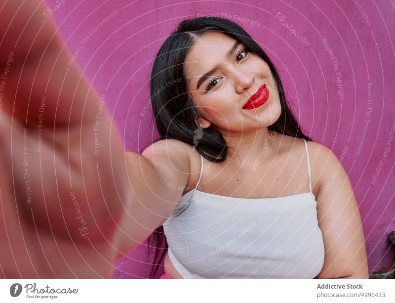 Junge ethnische Frau nimmt Selfie Lächeln Wand Glück Straße Vorschein Übergröße Stil modern jung Schwarzes Haar hell rote Lippen Optimist heiter mollig brünett