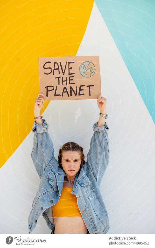 Junge Frau zeigt ökologisches Poster zeigen Plakat Umwelt Ökologie den Planeten retten hell protestieren Veranstaltung jung lässig Jeansstoff Transparente Wand