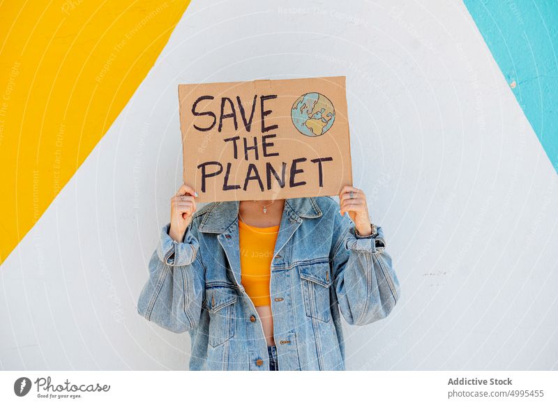 Anonyme Frau zeigt ökologisches Plakat zeigen Umwelt Ökologie den Planeten retten hell protestieren Veranstaltung jung lässig Jeansstoff Transparente Wand