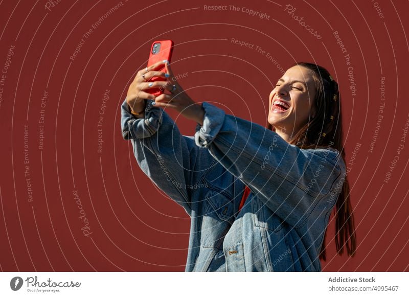 Junge Frau nimmt Selfie auf der Straße Lächeln Smartphone Wand Wochenende Glück hell jung Stil Sommer Funktelefon Apparatur heiter modern sorgenfrei