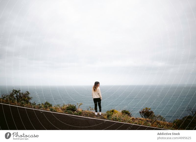 Frau steht auf der Straße in der Nähe des Meeres MEER Reisender wolkig Himmel Wochenende Ausflug Asphalt La Palma Kanarische Inseln Spaziergang Spanien lässig