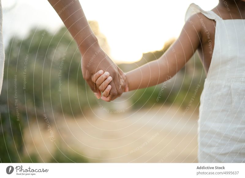 Crop schwarze Mutter und Kind halten Hände Händchenhalten Natur Sonnenuntergang Liebe Zusammensein Vertrauen Einheit Angebot Mama Eltern Kindheit Mutterschaft