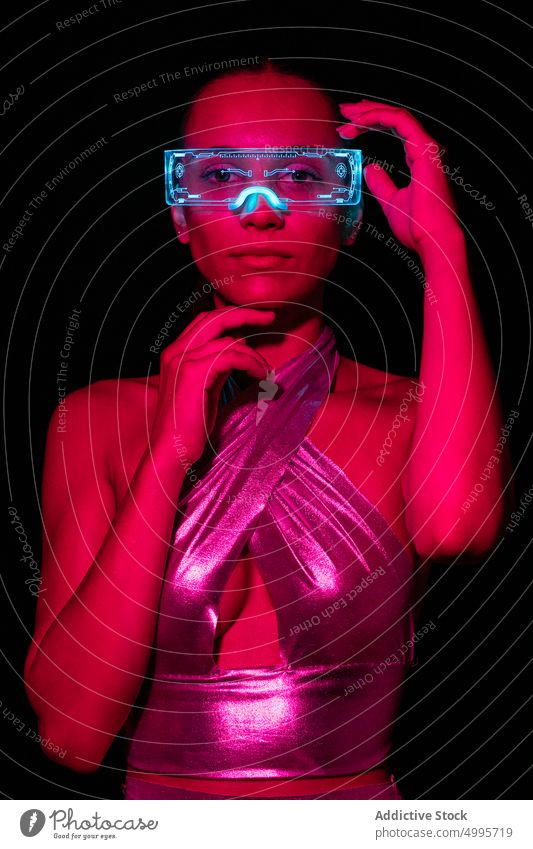 Junge Frau mit transparenter VR-Brille erkundet virtuelle Realität vor schwarzem Hintergrund Virtuelle Realität berühren interagieren Erfahrung simulieren