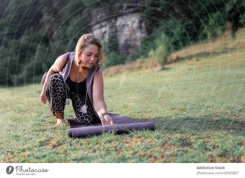 Frau rollt Matte auf Rasen aus abrollen Unterlage vorbereiten Sitzung Sprit meditieren Natur Sommer Gras Erwachsener üben Zen schamanische Heilung Wohlbefinden
