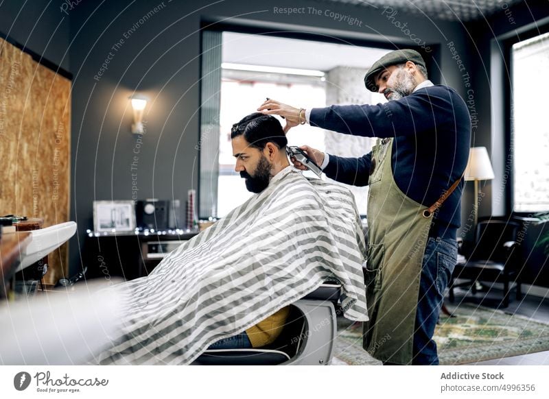 Ein Kunde erhält einen Haarschnitt in einem modernen Friseursalon Klient Salon hispanisch Pflege ethnisch Kap professionell Männer Dienst männlich Frisur