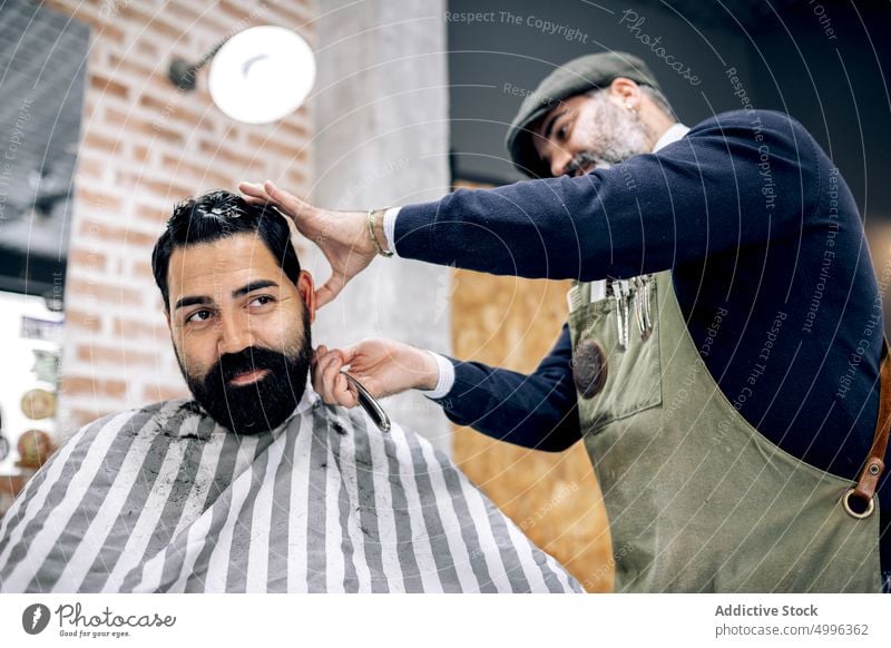 Friseur, der die Haare eines Kunden mit einem Rasiermesser schneidet Rasierer gerade Klinge Haarschnitt Klient geschnitten Pflege Barbershop reif Männer