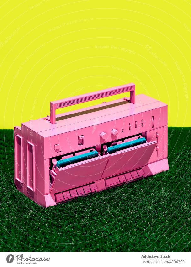 Rosa Retro-Kassettenrekorder auf Gras im Studio retro Tonbandgerät farbenfroh hell altehrwürdig Spieler Musik stereo Klebeband altmodisch lebhaft pulsierend