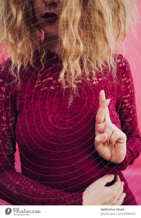 Frau mit gekreuzten Fingern im Studio Daumen drücken gestikulieren Zeichen Symbol Model Atelier blond gewelltes Haar zeigen manifestieren Stil Dame Hoffnung