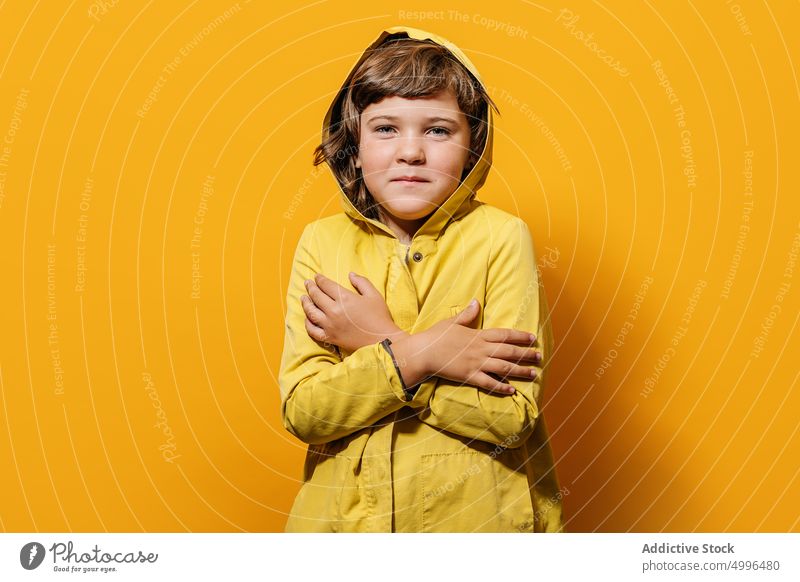 Ruhiger Junge in trendigem Outfit steht mit verschränkten Armen vor gelbem Hintergrund Umarmung Windstille Umarmen Kindheit Stil Individualität