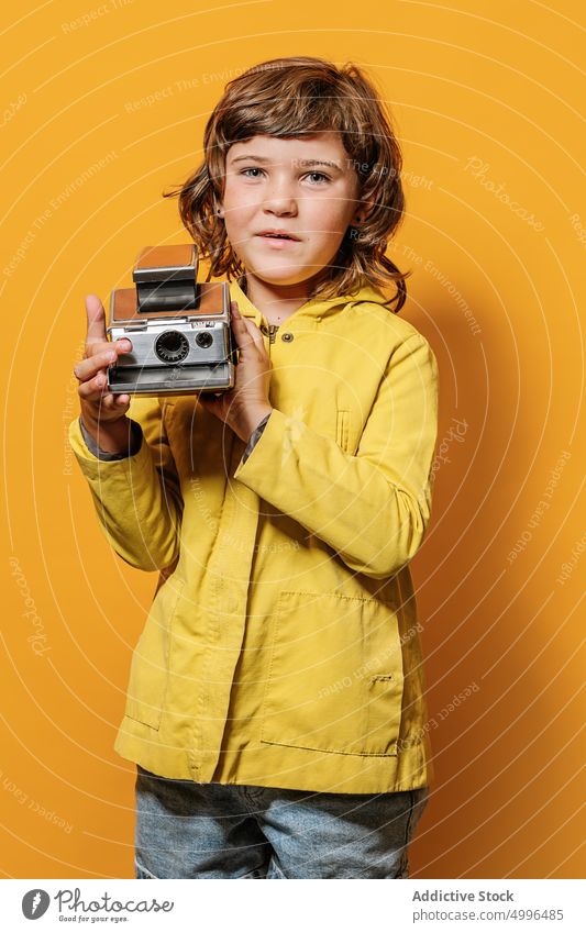 Mädchen fotografiert mit einer alten Kamera an einer gelben Wand im Studio farbenfroh fotografieren Stil Fotograf Herbst Porträt Fotoapparat Kindheit Linse