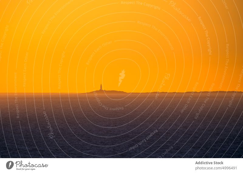Abgelegenes Leuchtfeuer auf einer Insel unter orangefarbenem Himmel Leuchtturm Sonnenuntergang MEER Abend Meer Dämmerung Landschaft sehr wenige majestätisch