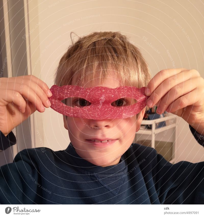 Kindheit | Salami-Superheld beim Abendbrot | Oder: isst er noch oder spielt er schon? Mensch Junge Gesicht Porträt Auge Blick Blick in die Kamera Hände halten