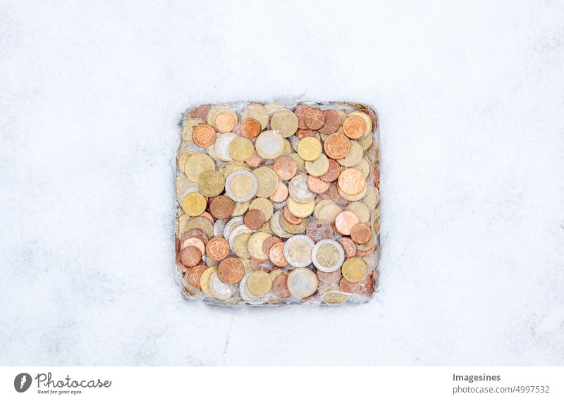 Eingefroren. Geld im Eis im Winter im Schnee. Euro-Münzen, Bargeld gefroren. Eingefrorendes Euro-Vermögen und Konzept der Finanzkrise Hintergründe Banken