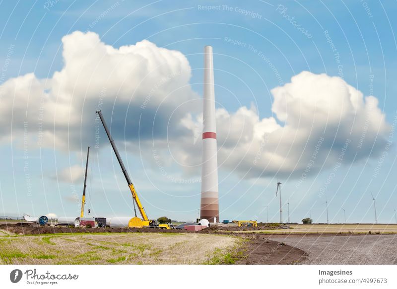 Aufbau und Montage einer Windkraftanlage per Kran. Ackerland mit Bauarbeiten im Windpark Wörrstadt, Deutschland. Energiesparkonzept aus dem Windkraftanlagenbau