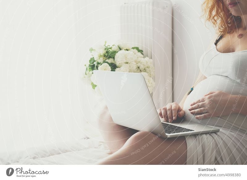 Junge schwangere Frau entspannt sich auf dem Bett mit einem Laptop Schwangerschaft Morgen jung Mädchen Sommersprossen Sonntag entspannend sich[Akk] entspannen