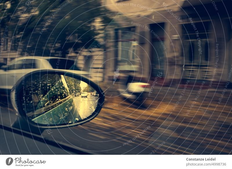 Straßenszene im Außenspiegel und Blick auf Hausfassade und Roller in ICM-Technik trübes Wetter Gebäude Stadtzentrum regnerisch Autoverkehr Tourismus