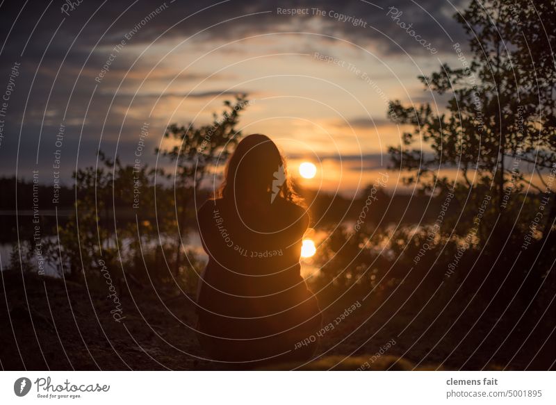 Mädchen schaut in den Sonnenuntergang am See Schweden von hinten Frau orange Wolken Himmel Spiegelung zentriert Ruhe Entspannung Fokus