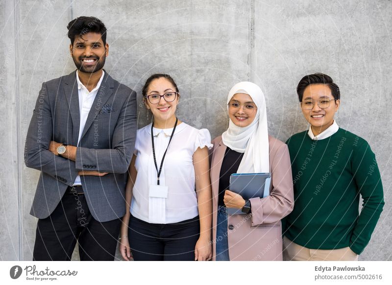 Aufnahme einer kleinen, bunt gemischten Gruppe von Geschäftsleuten, die vor einer grauen Wand stehen multirassische Gruppe Team Vielfalt Teamwork muslimisch