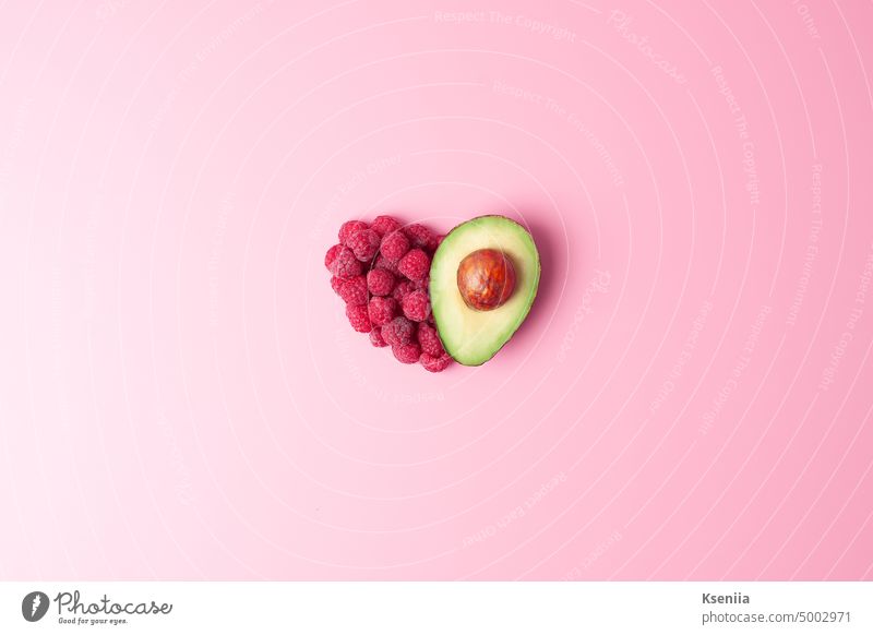 Kreatives Sommerkonzept. Herzform aus frischen Beeren und Avocado auf rosa Hintergrund. Flat lay, copy space. Biografie Frühstück Konzept Essen zubereiten