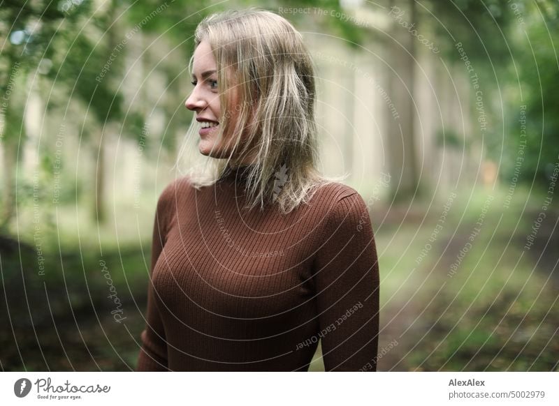 Junge, blonde Frau steht im Wald und lächelt glücklich in die Kamera junge Frau feminin schön Jugendliche Portrait Erwachsene natürlich authentisch Gefühle