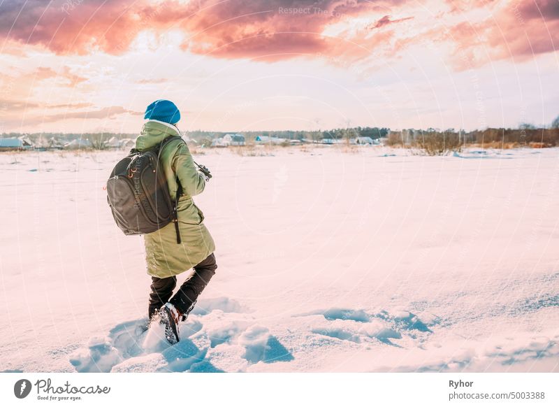 Junge Frau Tourist Lady Photograph Taking Pictures Of Snowy Landscape In Sunny Winter Day. Aktiver Lebensstil mit Rucksack und Kamera. Geänderter Sonnenuntergang Himmel