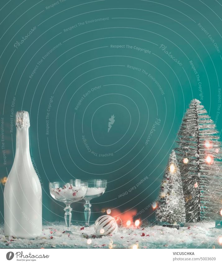 Weihnachten und Neujahr Hintergrund mit Flasche Champagner, Phantasie Gläser mit Schnee, Weihnachtskugeln, Tannenbäume und Fee Licht Bokeh. Urlaub Stillleben