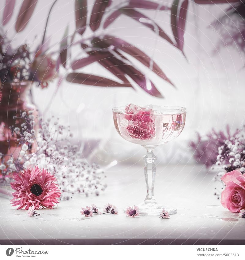 Schickes Getränk in einem großen Glas Champagner mit rosa Eiswürfeln und lila Blumen und Blättern. ausgefallen trinken breit purpur Ordnung Veranstaltung