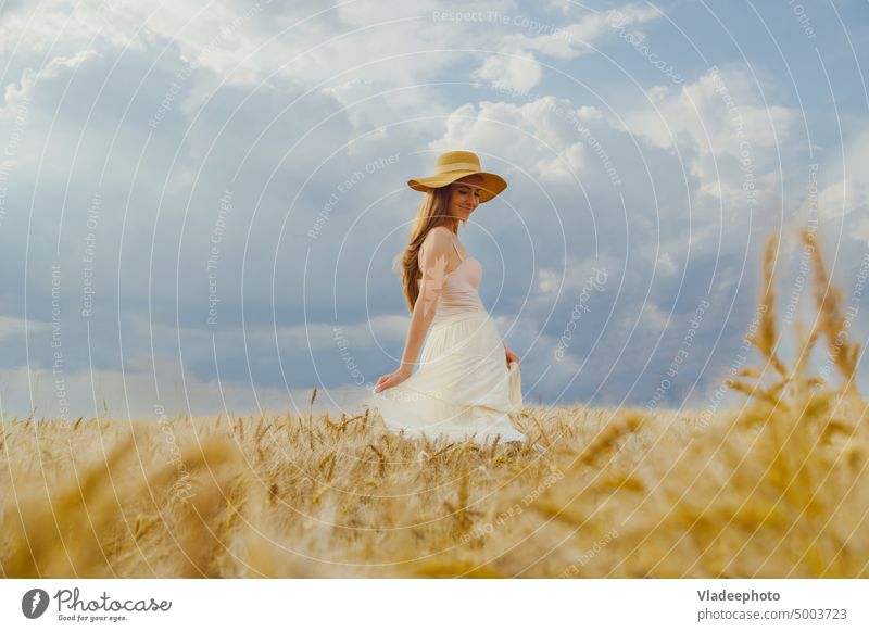 Frau in ländlicher Kleidung und Hut tanzt allein in einem Weizenfeld Feld Sommer Rücken Tanzen Freiheit Ansicht Roggen Behaarung blond Weide blau elegant