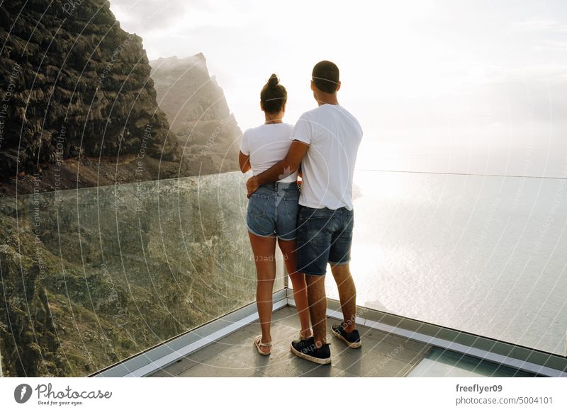 Junges Paar auf einem Aussichtspunkt vor vulkanischen Klippen und dem Meer Liebe Flitterwochen jung Sonnenuntergang Kaukasier Textfreiraum Steine