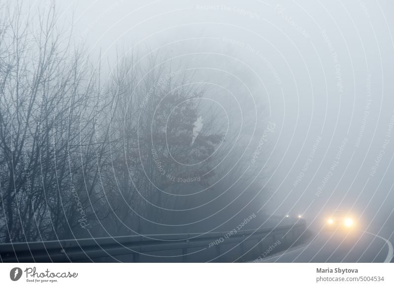 Dichter Nebel auf der Autobahn in Europa an einem Wintertag. Die Gefahr des Fahrens von Fahrzeugen auf Straßen bei schlechtem, nebligem Wetter. Versicherung der Sicherheit von Fahrern und Fahrzeugen.