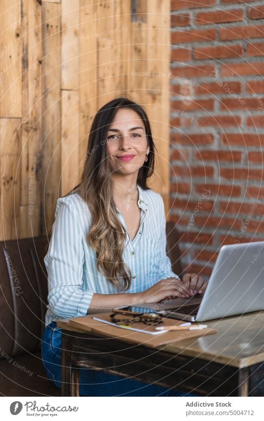 Lächelnde Freiberuflerin mit Laptop in einem Café Frau freiberuflich benutzend Projekt Glück Daten Freude abgelegen Telearbeit Tisch froh jung smart lässig