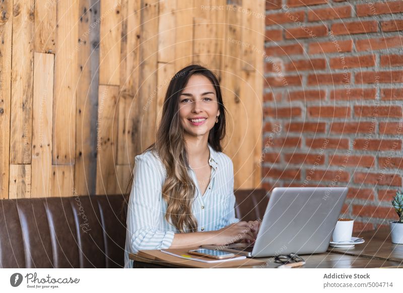 Lächelnde Freiberuflerin mit Laptop in einem Café Frau freiberuflich benutzend Projekt Glück Daten Freude abgelegen Telearbeit Tisch froh jung smart lässig