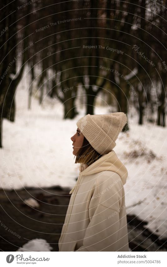 Junge Frau in warmer Kleidung im Winterwald stehend warme Kleidung Schnee kalt verträumt Fluss Wald Winterzeit Natur Wälder Hut Melancholie Hand-in-Tasche