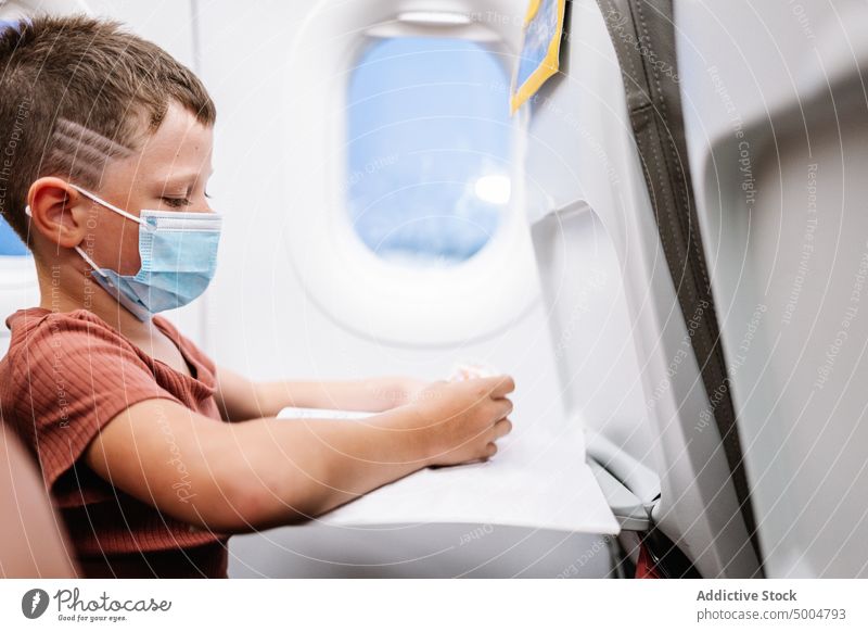Junge benutzt Smartphone im Flugzeug spielen Videospiel Ebene benutzend Pandemie Passagier online reisen Bund 19 Coronavirus Kind Verkehr Kindheit Funktelefon