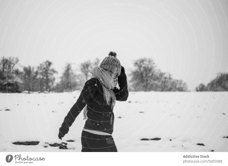 Positive Frau, die an einem düsteren Wintertag durch verschneites Gelände läuft Spaziergang Natur Glück Schnee Landschaft positiv Schneefall Wiese Baum laublos