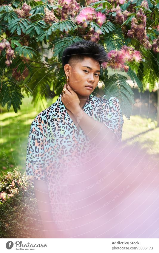 Filipino Transgender Frau stehend auf Garten Baum Blütezeit lgbt nicht binär Blume ethnisch asiatisch Filipinos Vorschein Laubwerk queer kein Make-up