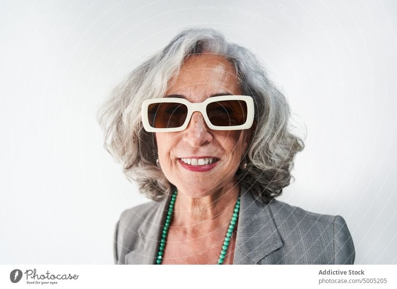 Fröhliche ältere Frau mit modischer Sonnenbrille Lächeln Stil Glück Vorschein Porträt Accessoire graues Haar Rentnerin Senior gealtert Geschäftsfrau froh heiter